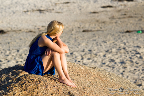 Blonde woman sitting on a rock.